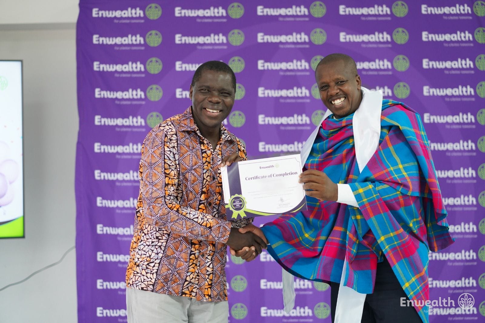 A graduate wearing a traditional shuka receiving his SEED Certificate of Completion.