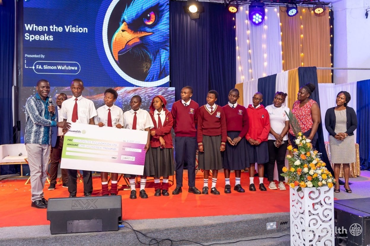 Students in school uniform on stage receiving an oversized cheque.