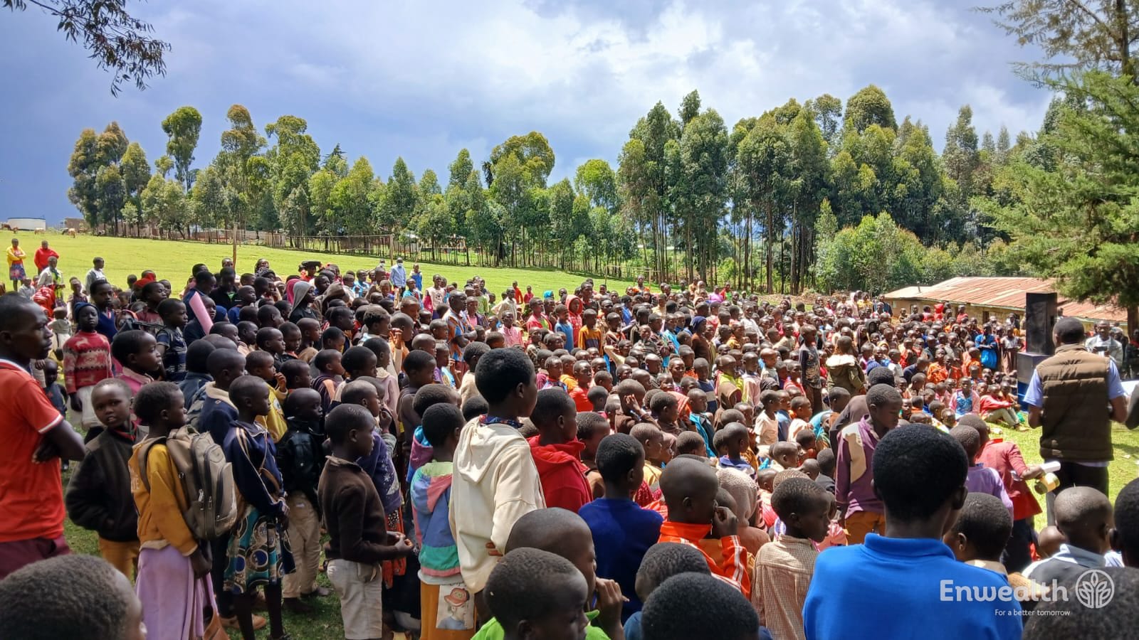 Several hundred children and young people gathered on a hillside at a mission event.